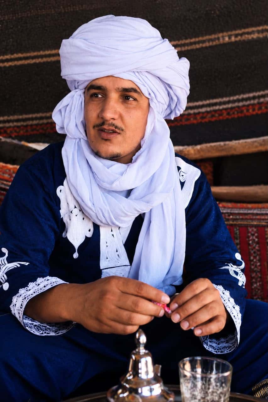 Moroccan desert host wearing a traditional blue turban inside a Sahara camp